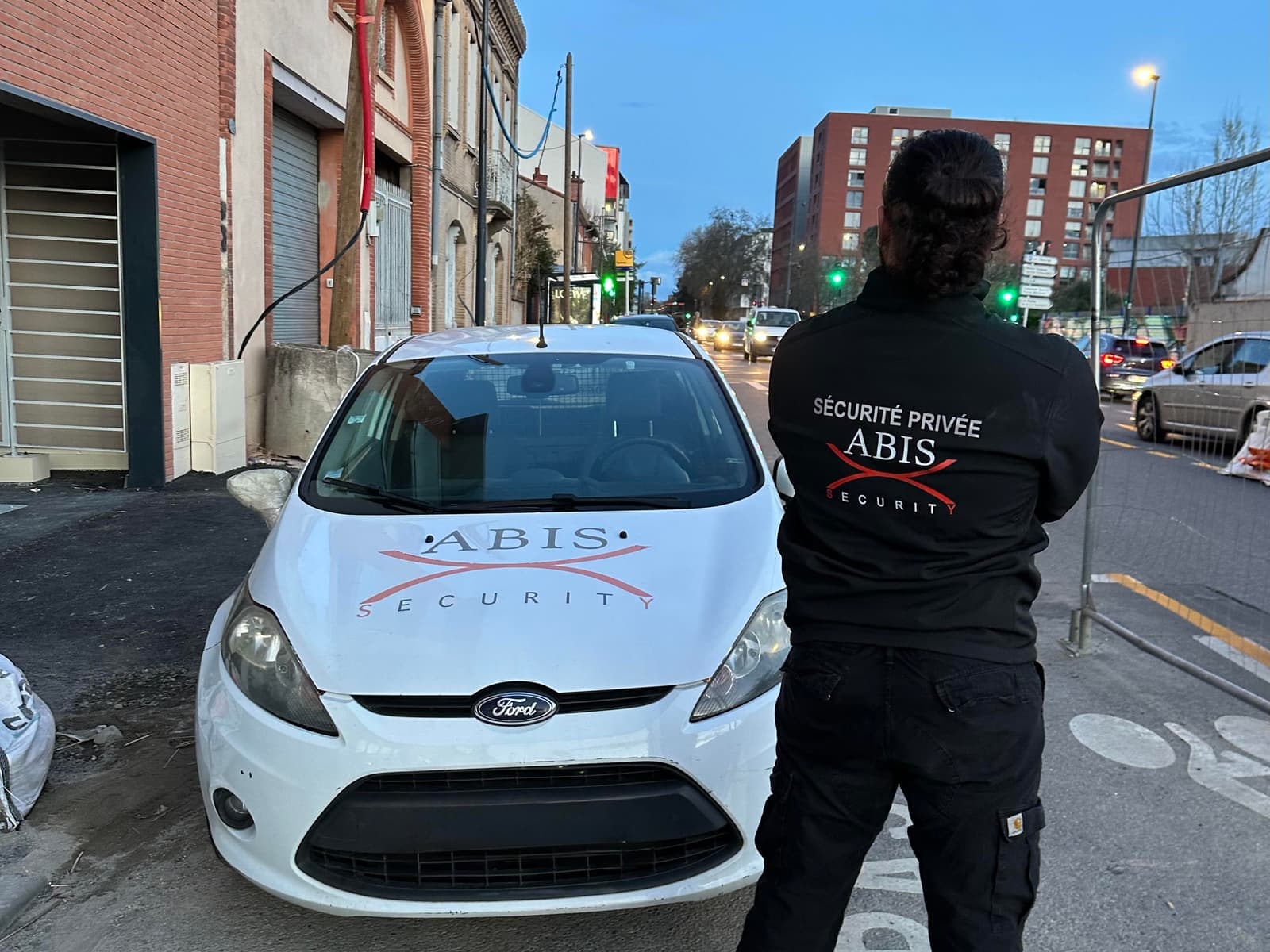 Véhicule d'intervention Abis Security et son agent en tenue, en rue à la tombée de la nuit
