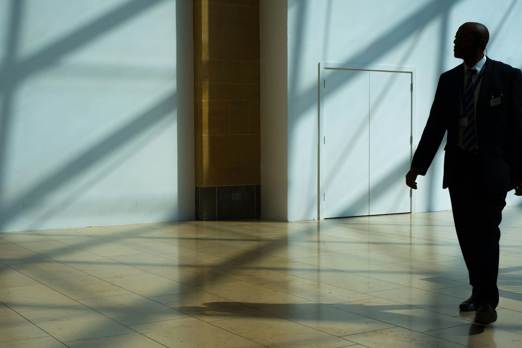 Homme en costume traversant le hall lumineux d'un immeuble de bureaux